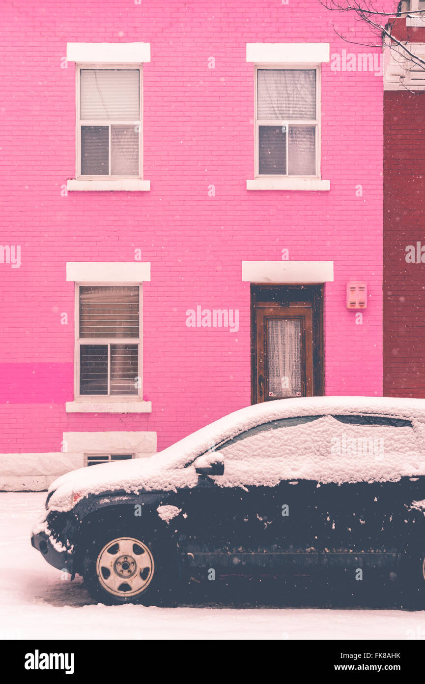 Montréal, CA, 7 mars 2016. voiture noire couverte de neige en face de rose maison traditionnelle pendant une tempête de neige Banque D'Images
