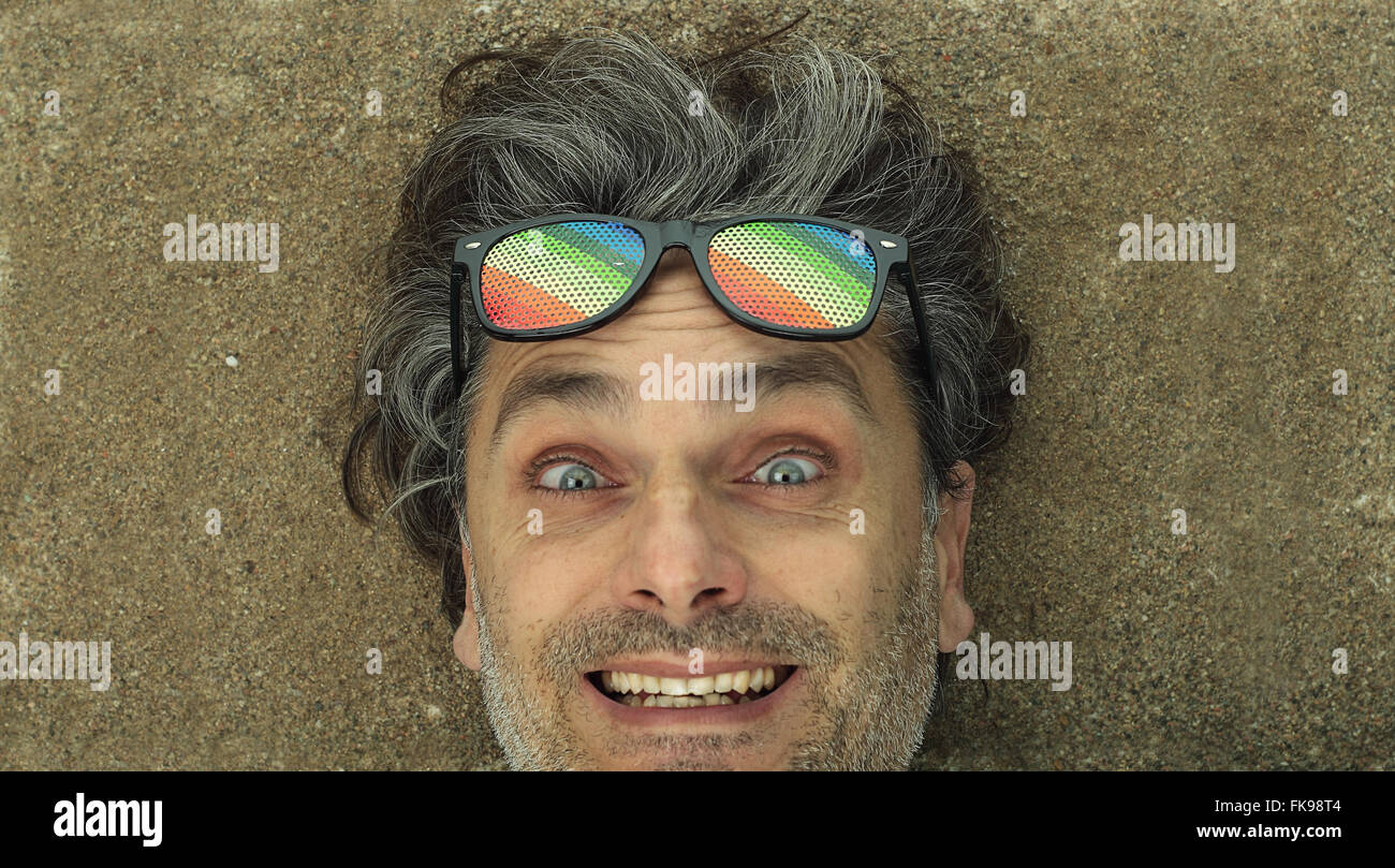 Homme avec cheveux blancs portant sur une plage de sable Banque D'Images