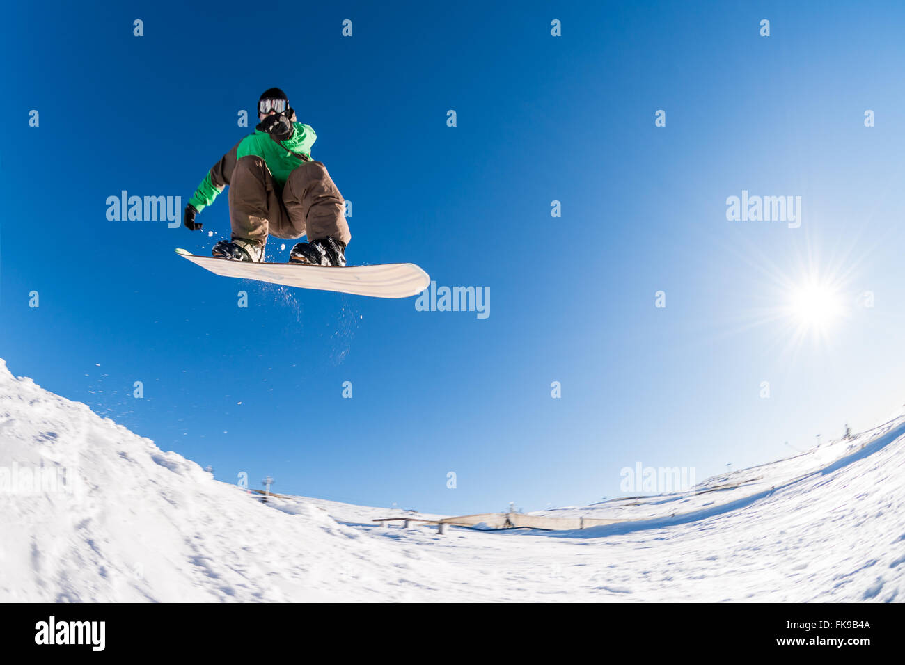 Snowboarder de l'exécution d'un saut radical contre le ciel bleu. Banque D'Images
