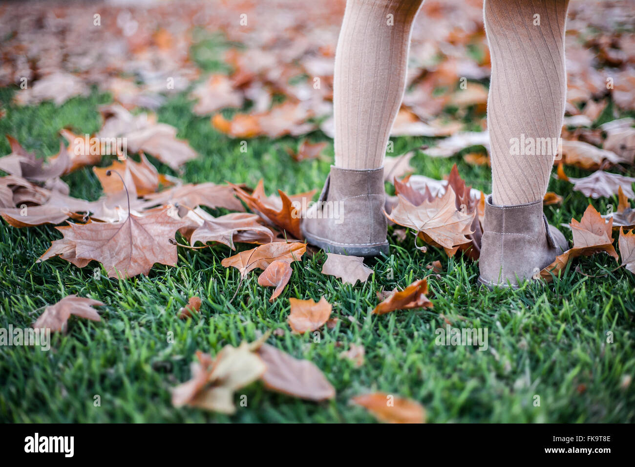 Happy little girl jouant avec les feuilles d'automne dans le parc. Elle est la marche sur les feuilles jaunes en automne park Banque D'Images