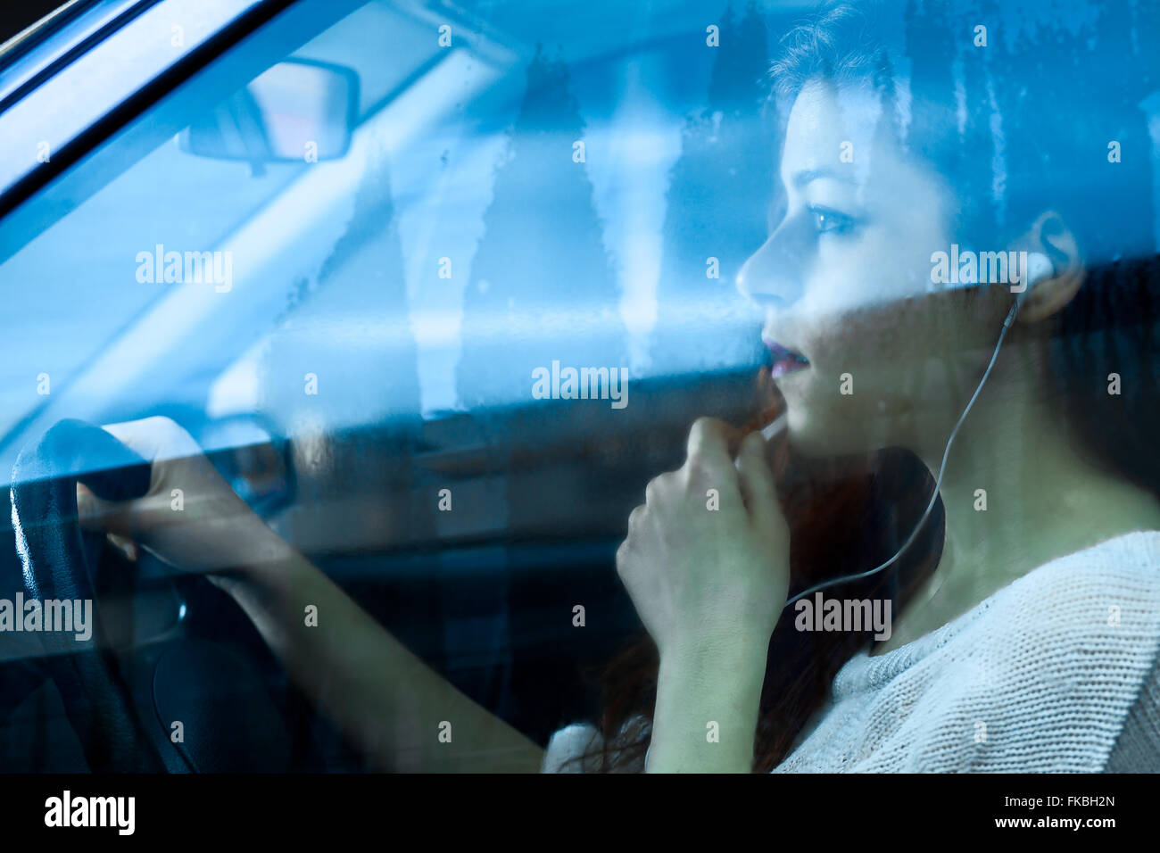Femme parlant dans un micro avec les écouteurs en conduisant une voiture Banque D'Images