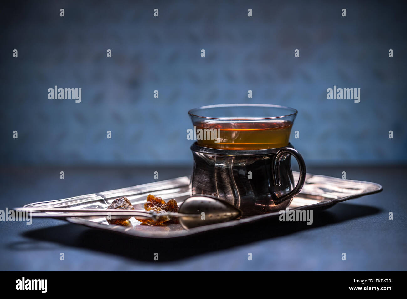 Le thé chaud dans la tasse en verre avec poignée en métal Banque D'Images