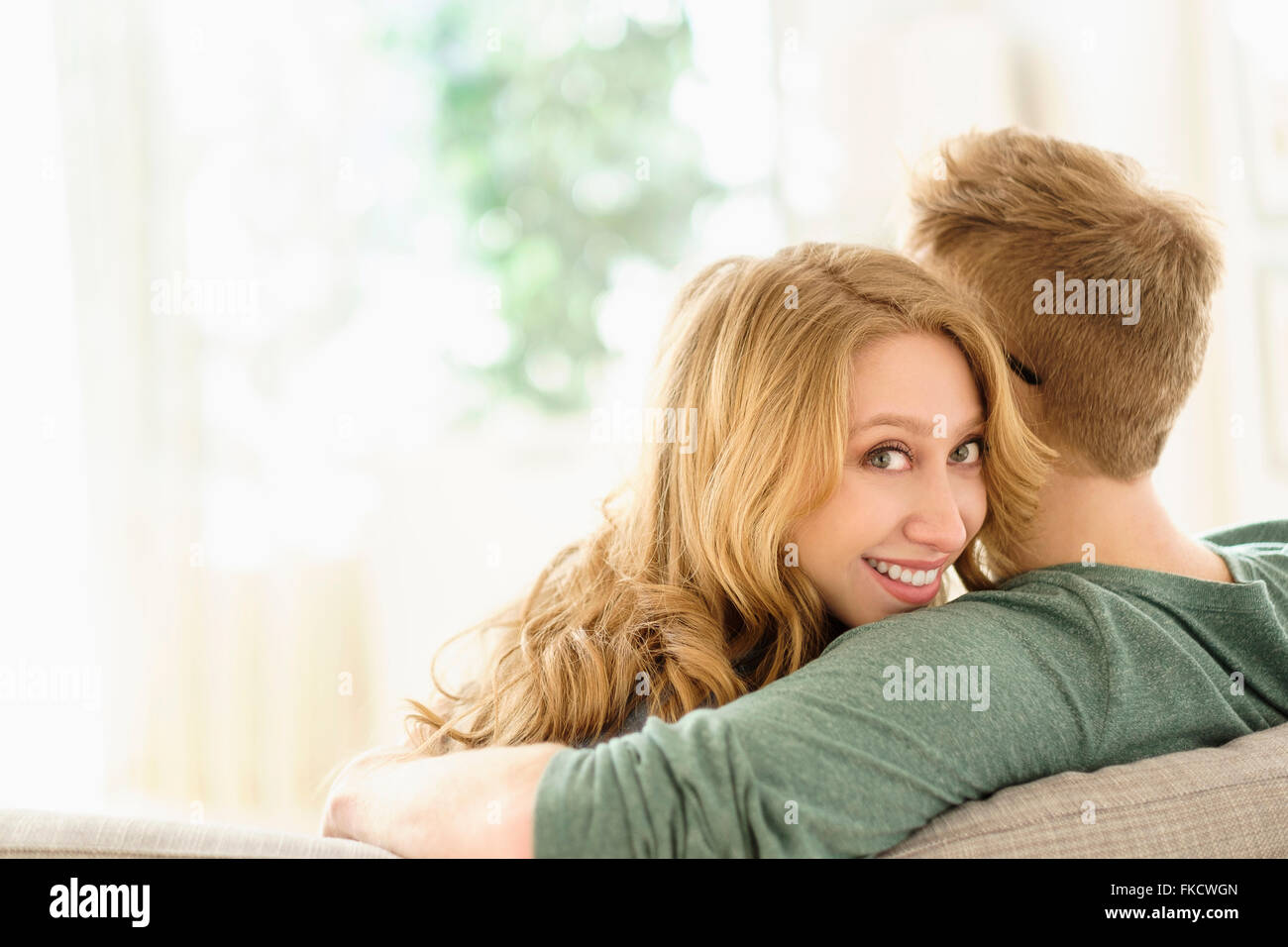 Portrait of young woman hugging boyfriend sur canapé Banque D'Images