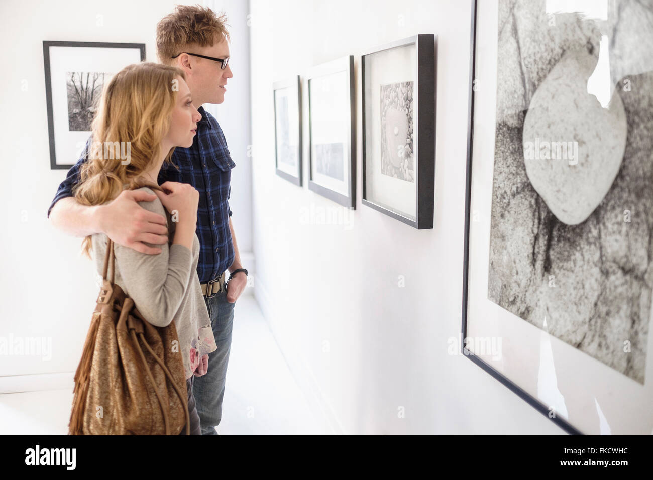 Jeune couple looking at photographs at museum Banque D'Images