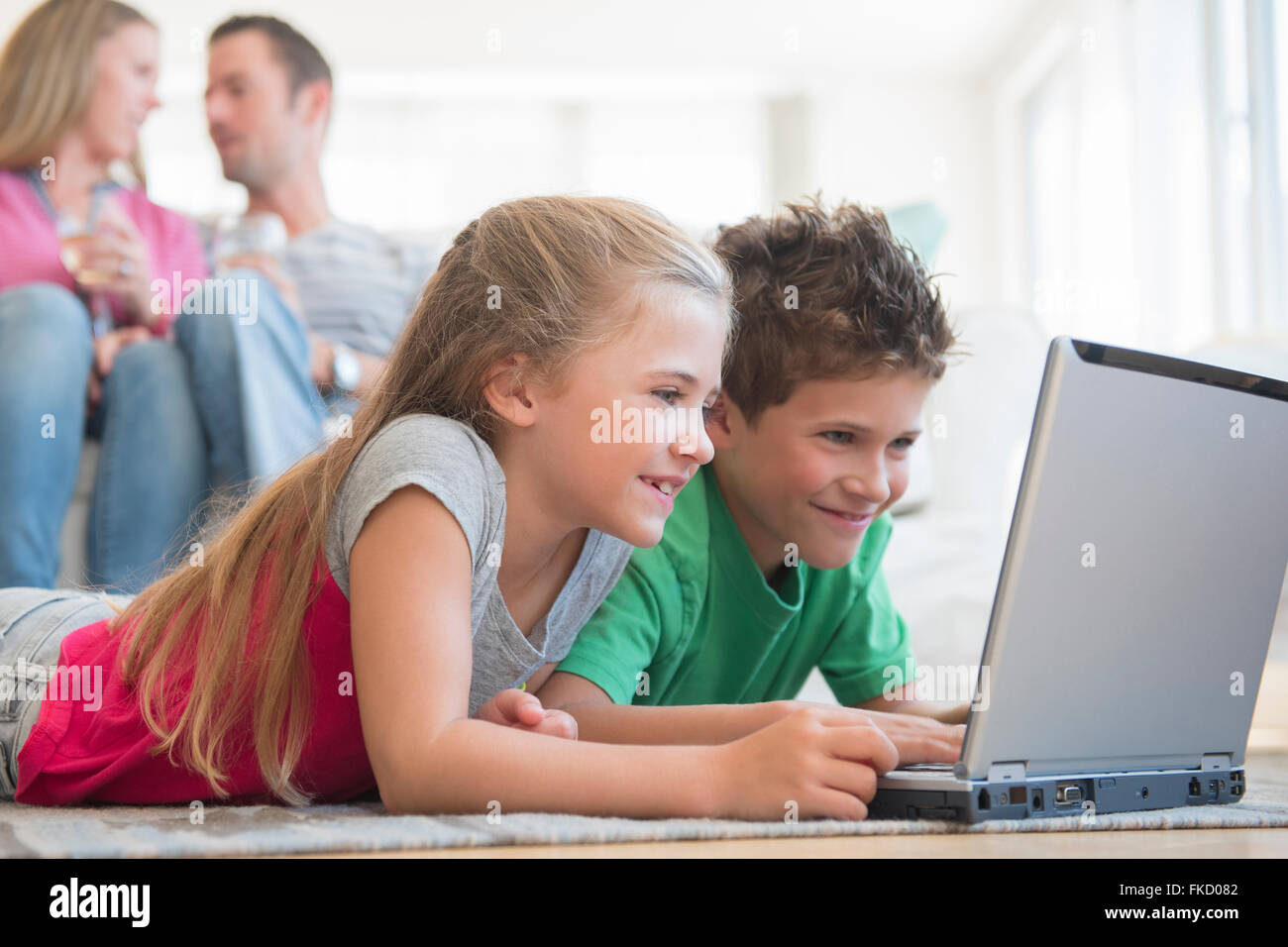 Boy and girl (6-7, 8-9) lying on floor and using laptop Banque D'Images