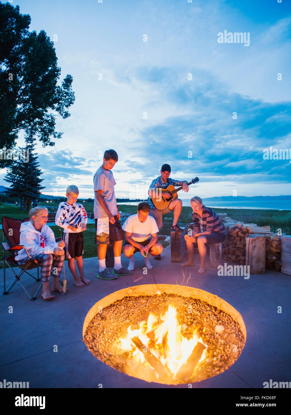 Les parents avec enfants (8-9, 10-11, 16-17) assis en face de camp et jouer de la guitare Banque D'Images