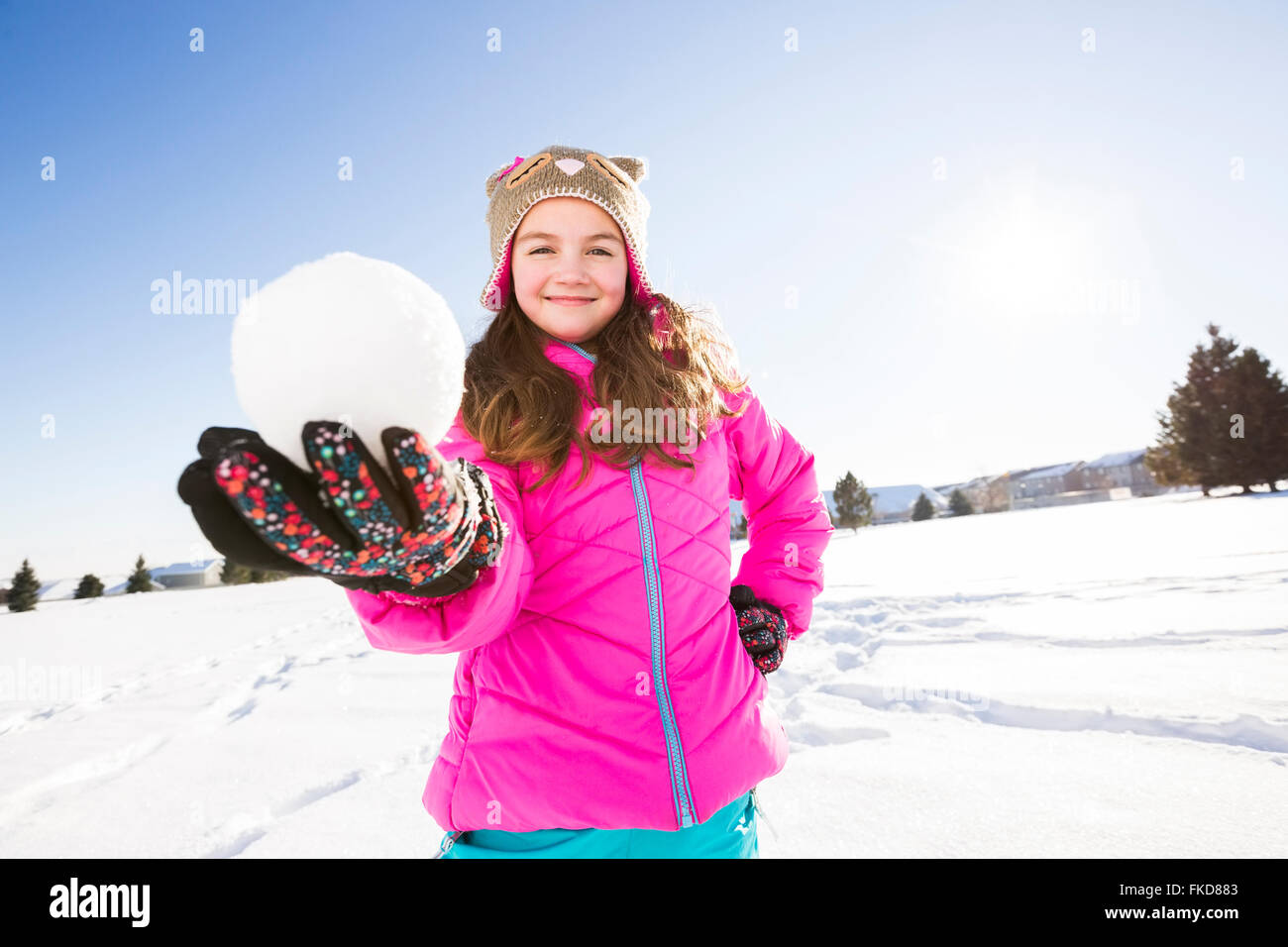 Girl (10-11) holding snowball dans dossier rose Banque D'Images