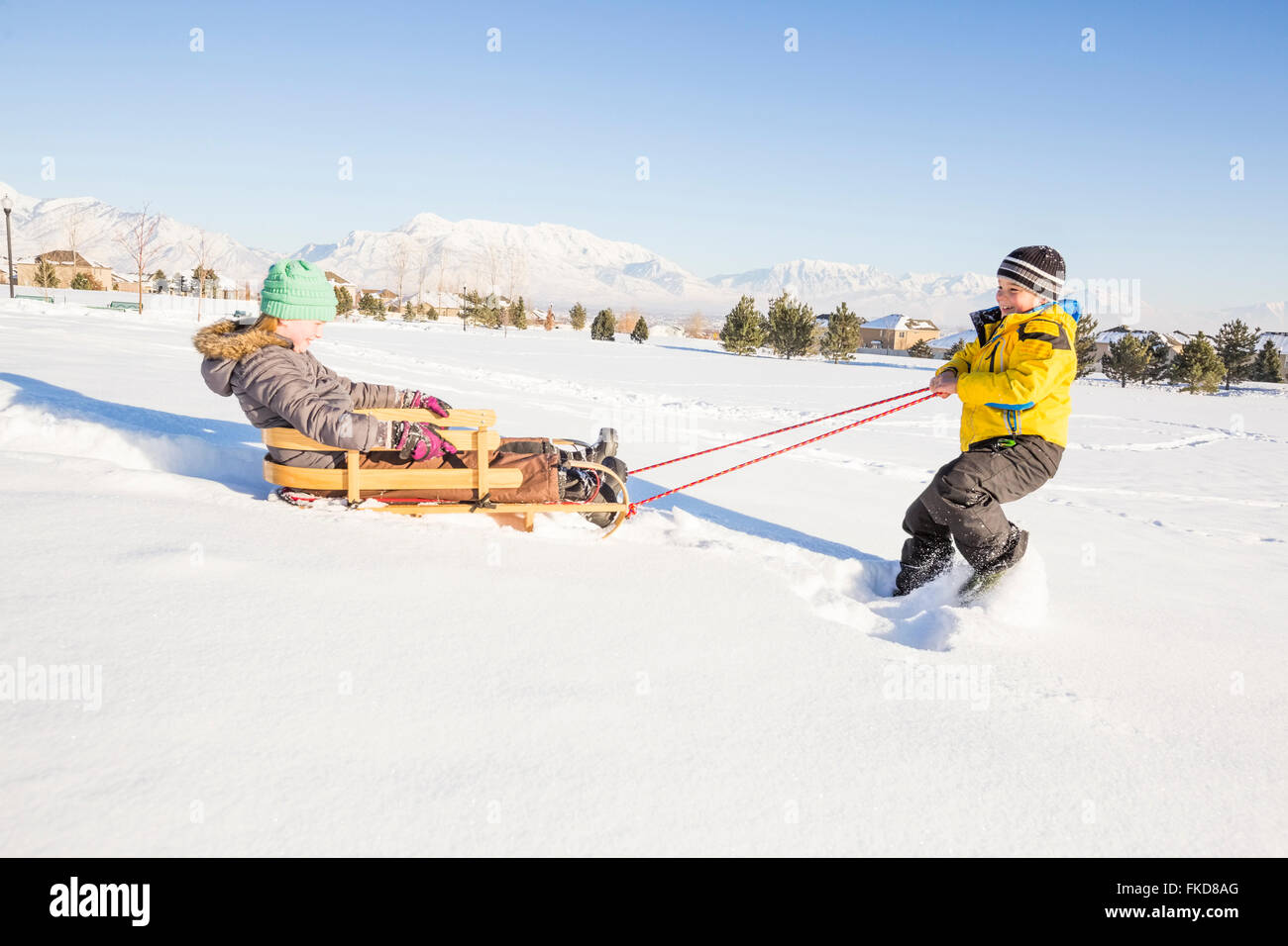 Enfants (8-9) en jouant avec la neige en traîneau Banque D'Images
