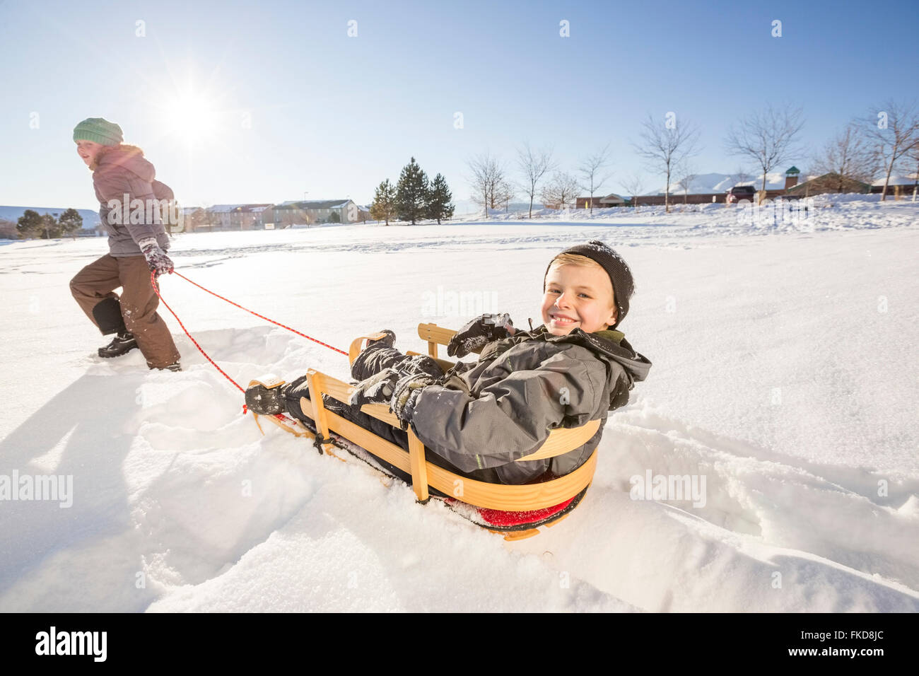 Enfants (8-9) en jouant avec la neige en traîneau Banque D'Images
