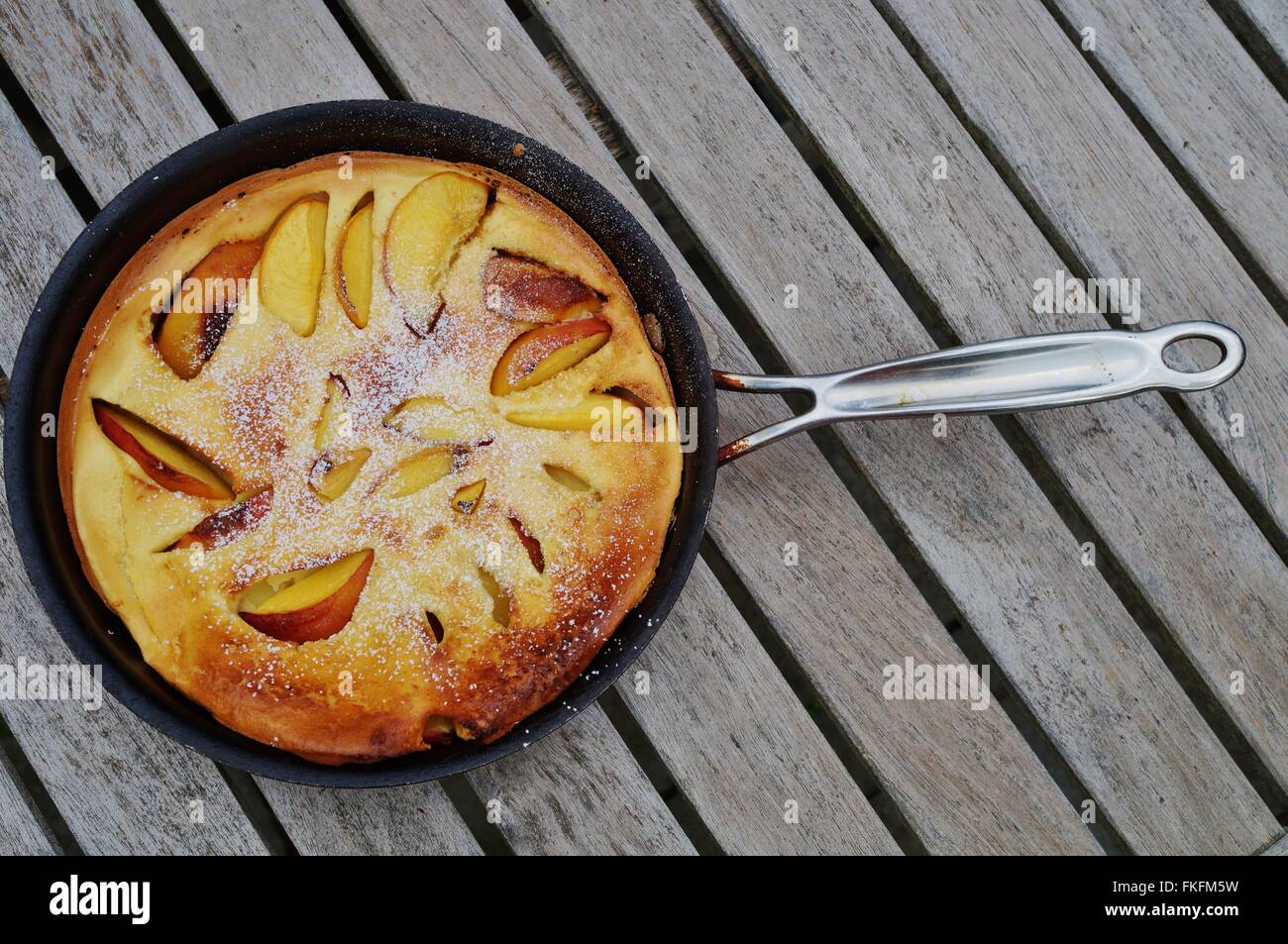 Peach Dutch pancake dans une casserole avec du sucre en poudre Banque D'Images