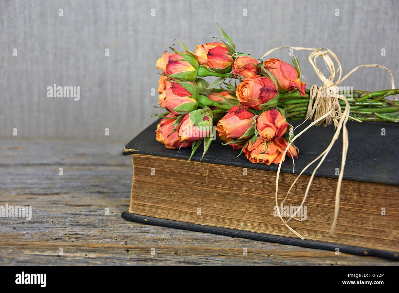 Bouquet de roses orange avec du raphia noeud sur livre ancien. Banque D'Images