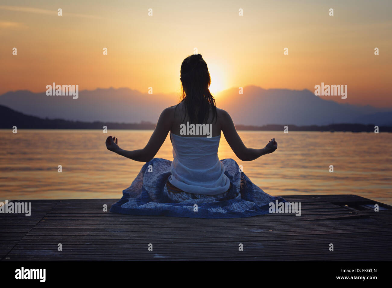 Femme silhouette devant le coucher du soleil sur le lac d'or colorés . Le yoga et la méditation Banque D'Images