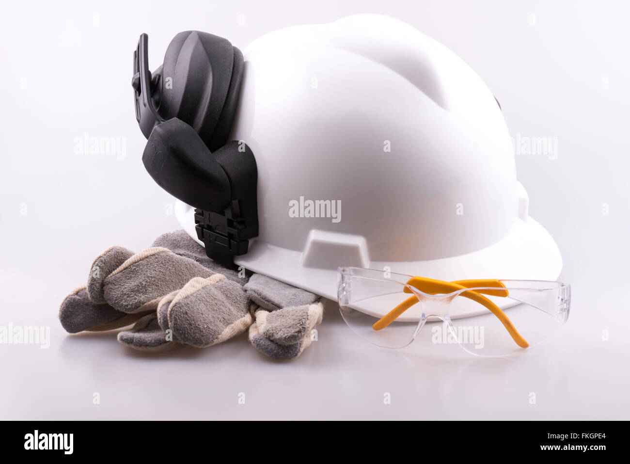 Casque, protège-oreilles, gants et lunettes de sécurité sur un fond blanc Banque D'Images
