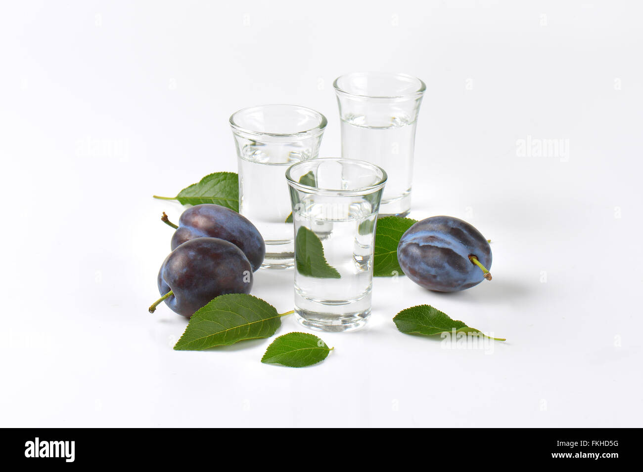 Slivovitz (prunes) et de prunes fraîches sur fond blanc Banque D'Images