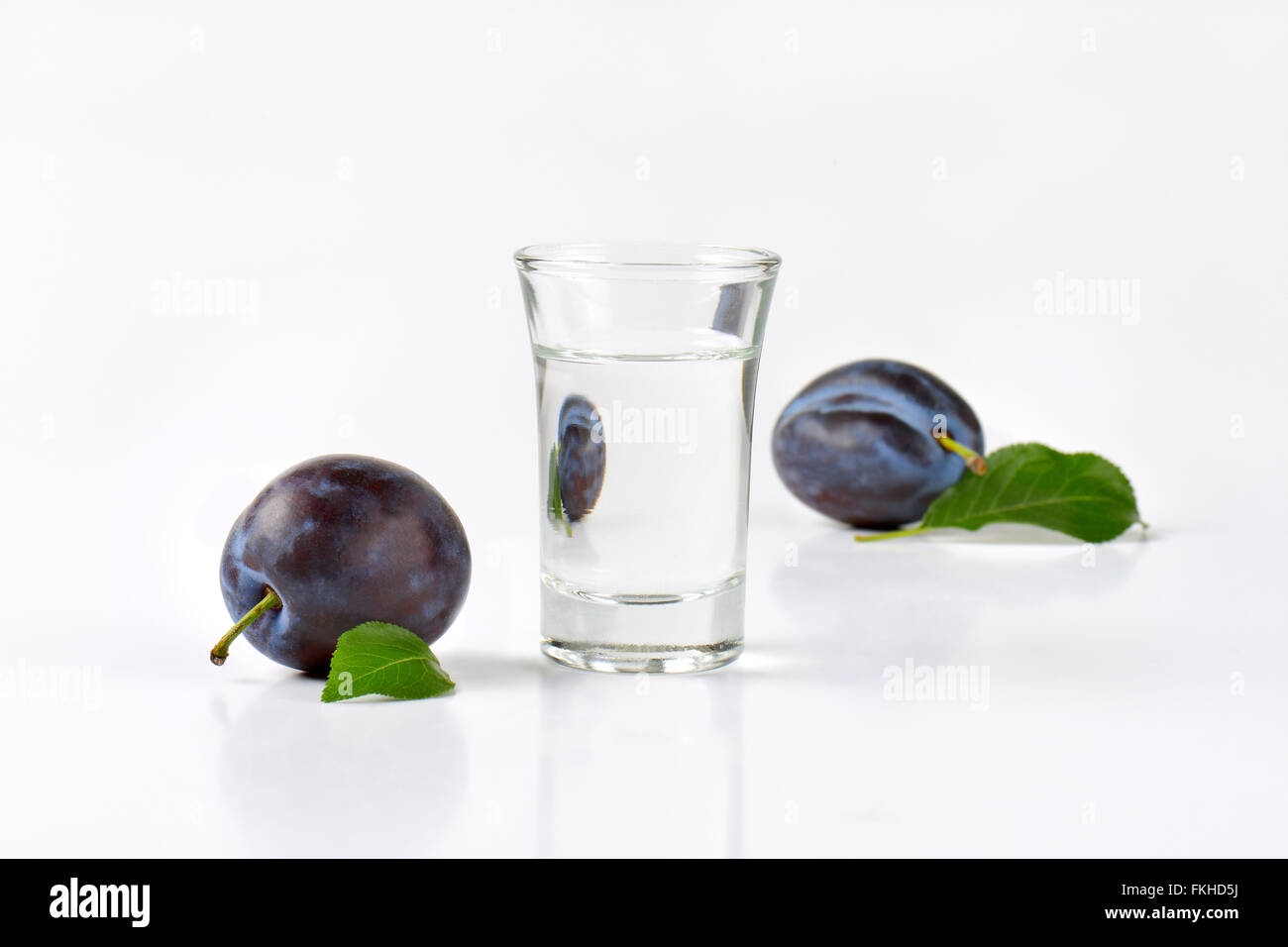 Slivovitz (prunes) et de prunes fraîches sur fond blanc Banque D'Images