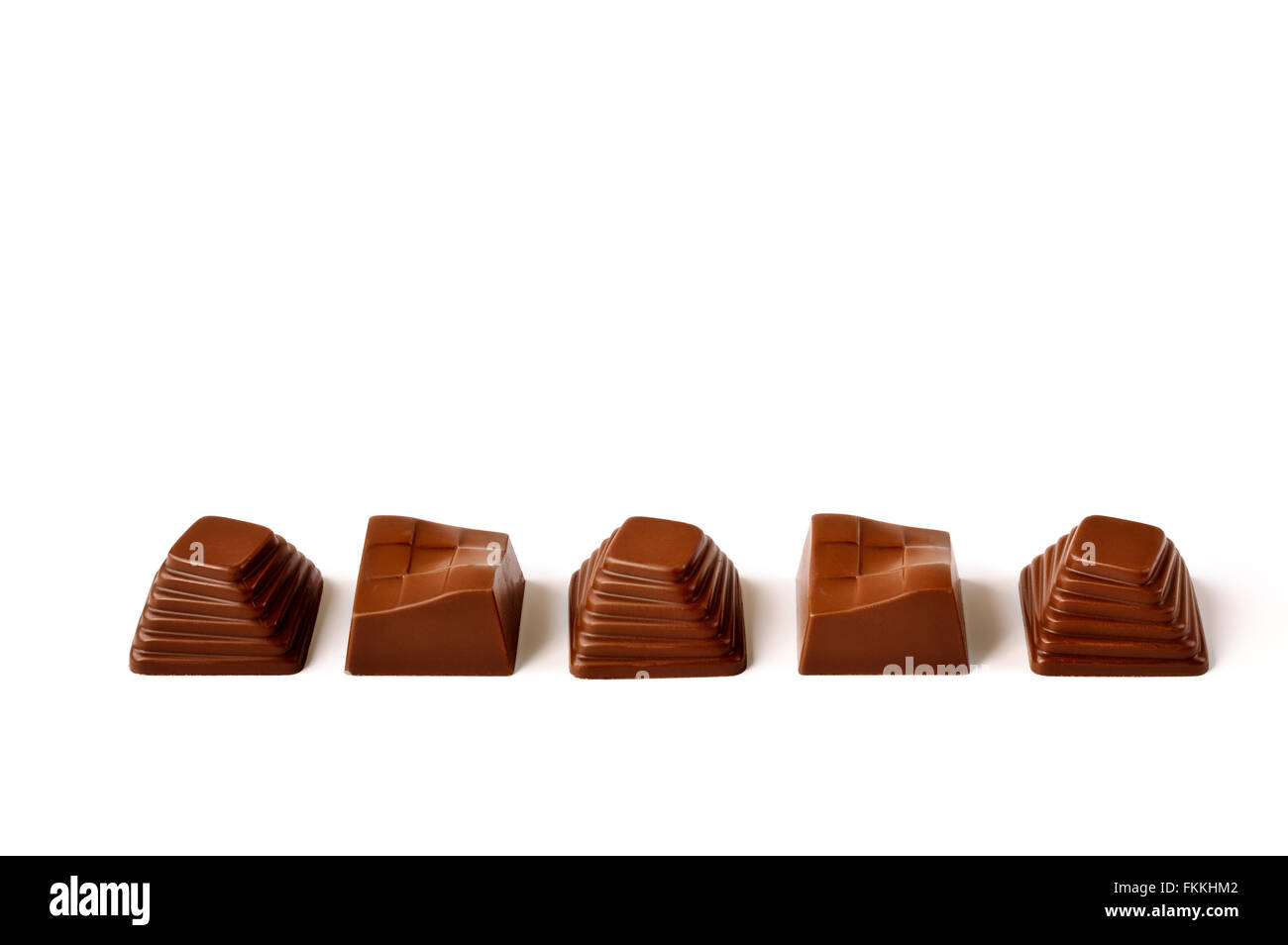 Blanc, noir et lait chocolat pralines dans une cuillère en céramique sur un fond texturé violet. Banque D'Images