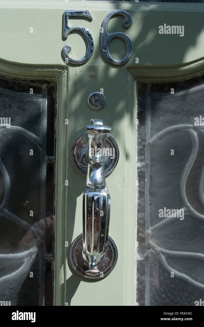 Un heurtoir sur une porte en verre vert lime, d'une maison d'habitation. Banque D'Images