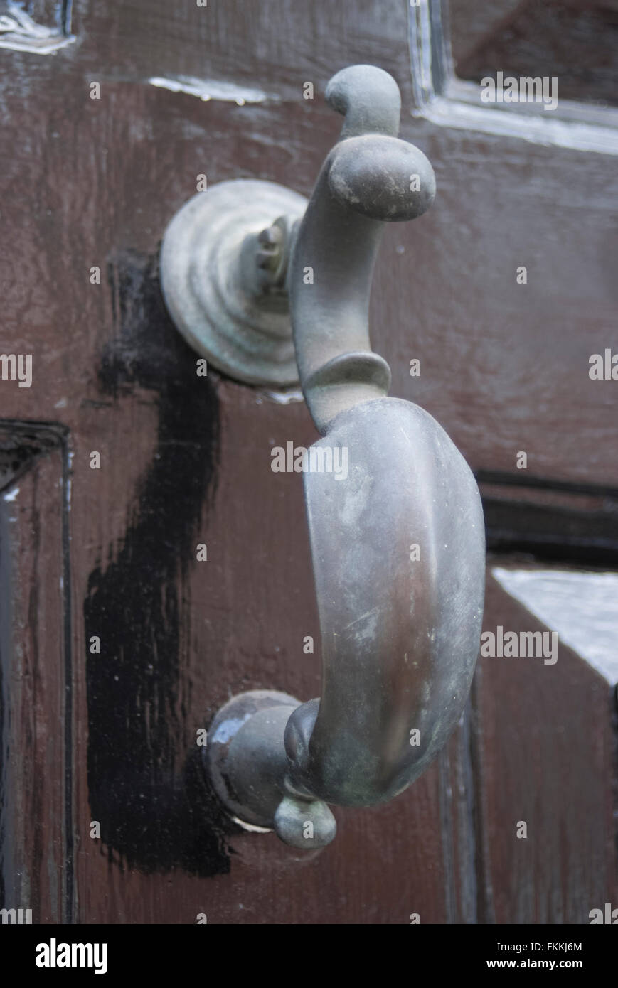 Un style ancien heurtoir sur une porte en verre en bois brun, d'une maison d'habitation. Banque D'Images