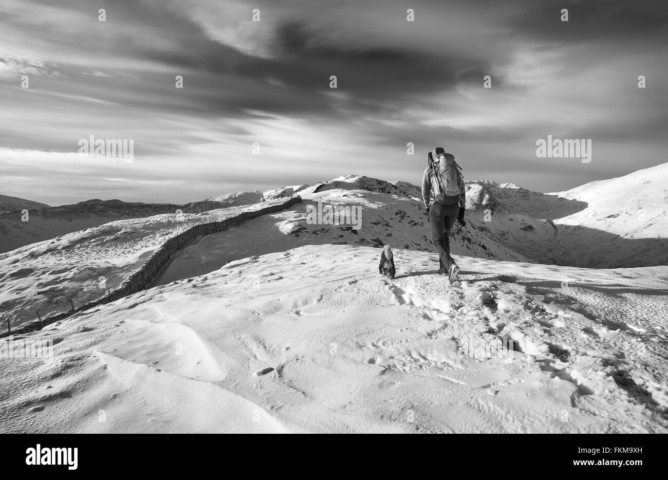 Randonnée randonneur leur chien sur les montagnes couvertes de neige au Royaume-Uni. La couleur du grain et styling appliqué Banque D'Images