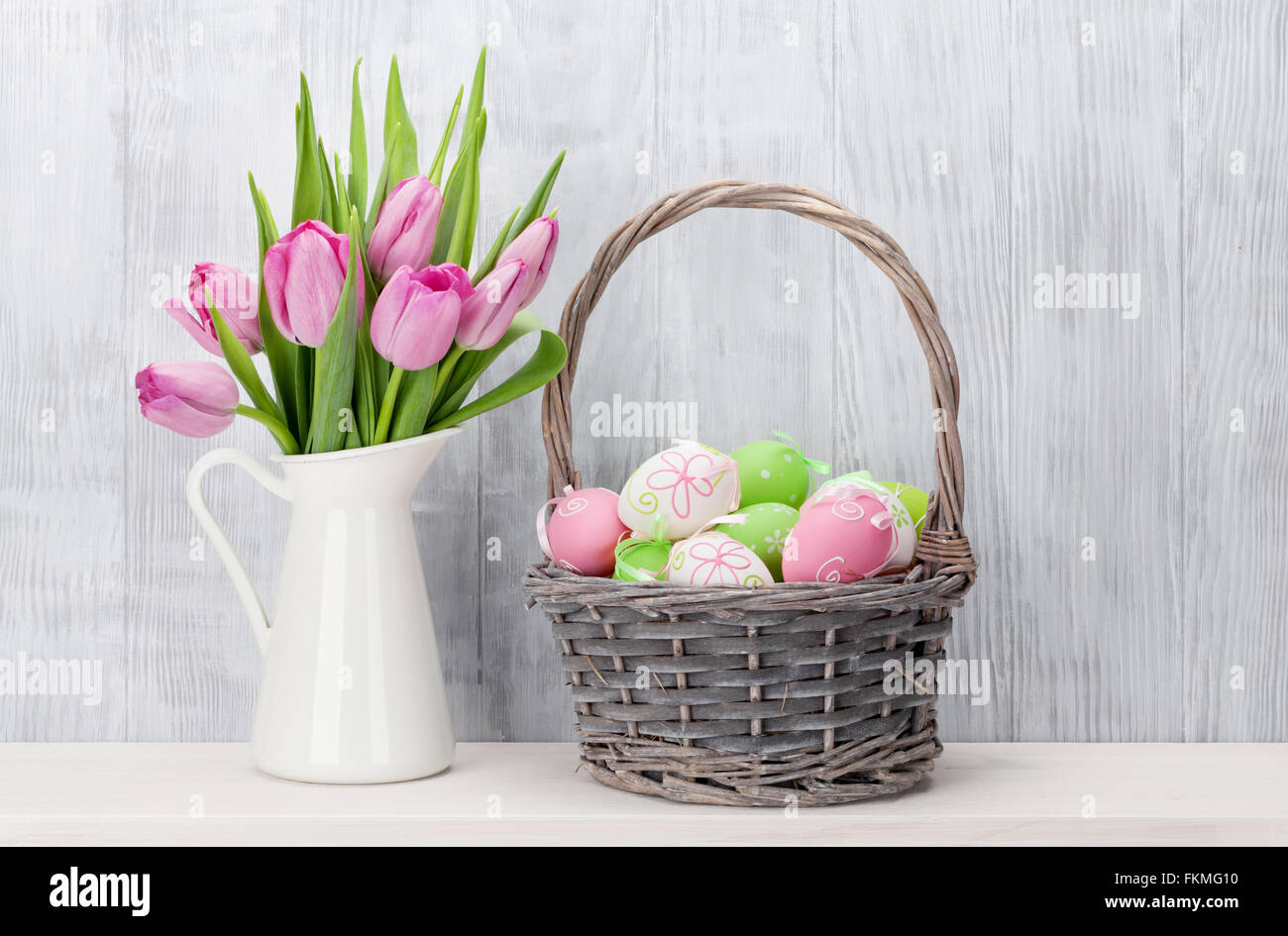 Oeufs de Pâques dans un panier et des tulipes sur la tablette en face de mur en bois Banque D'Images