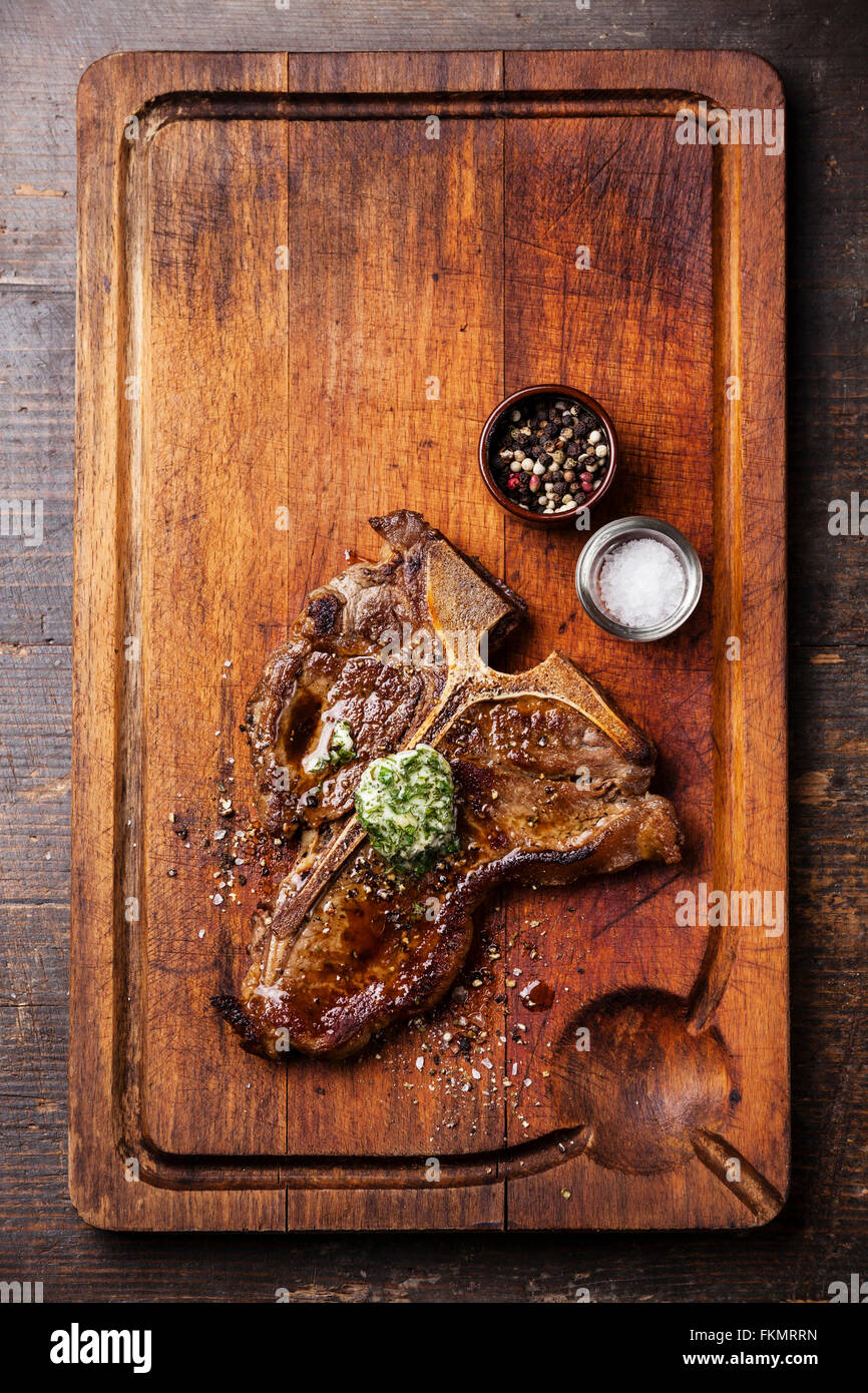 T-bone steak grillé au beurre d'herbes et de sel et poivre sur planche à découper en bois Banque D'Images