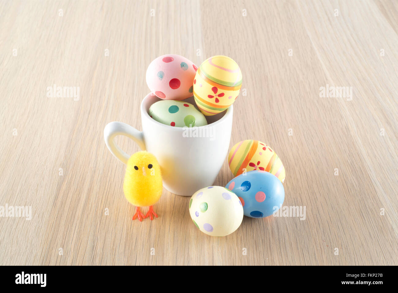 Pâques, petit poussin et les oeufs colorés dans une tasse à café Banque D'Images