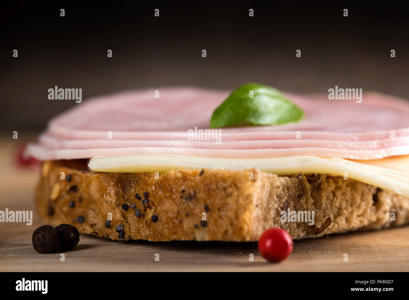 Close up of sandwich ouvert avec le salami, le fromage et le basilic sur fond de bois Banque D'Images
