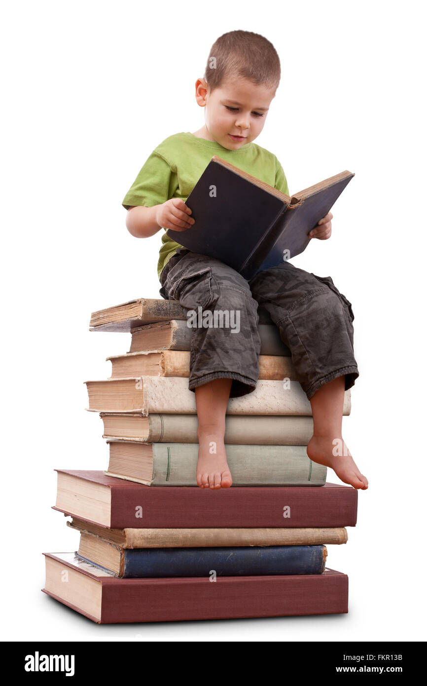 Garçon assis sur un gros tas de livres et lecture Banque D'Images