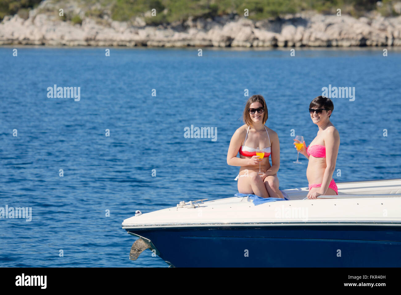 Les femmes de boire des cocktails sur boat in ocean Banque D'Images