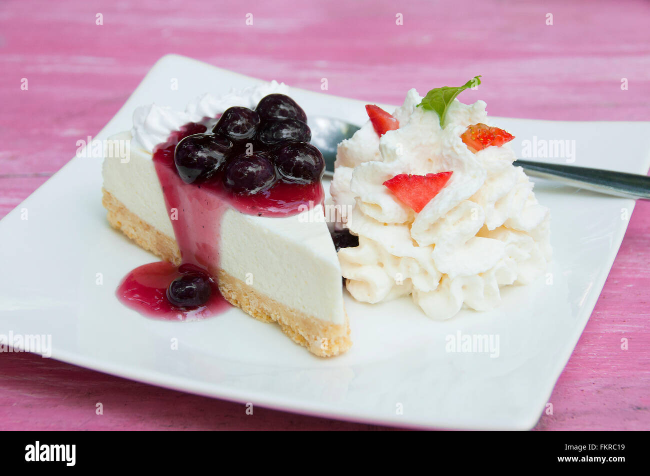 Blueberry cheesecake avec de la crème fouettée et les fraises en tranches dans le plat. Banque D'Images