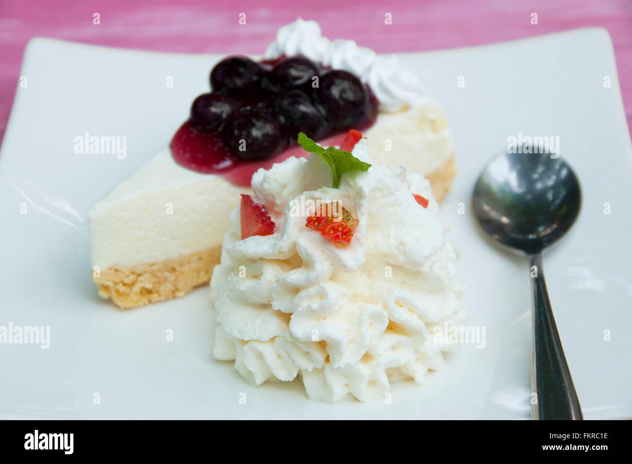 Blueberry cheesecake avec de la crème fouettée et les fraises en tranches dans le plat. Banque D'Images