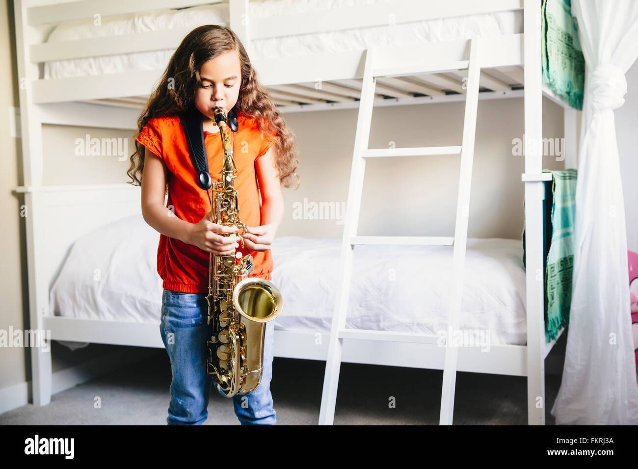 Mixed Race girl à jouer du saxophone dans la chambre Banque D'Images