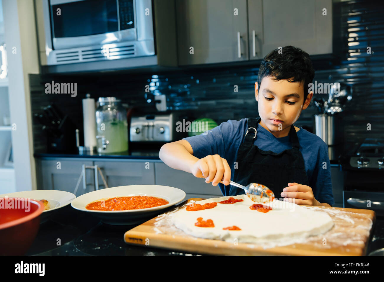 Mixed Race boy pizza dans la cuisine Banque D'Images