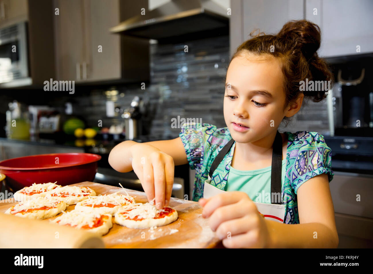 Mixed Race girl cooking in kitchen Banque D'Images