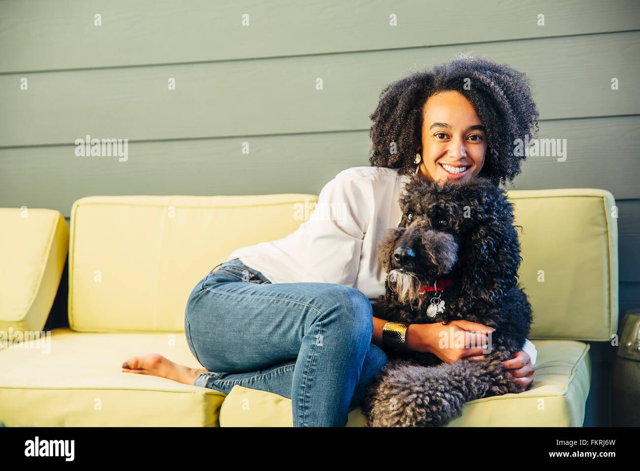 Mixed Race woman petting dog on sofa Banque D'Images