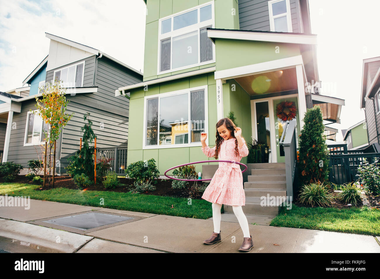 Mixed Race girl twirling hoop on sidewalk Banque D'Images