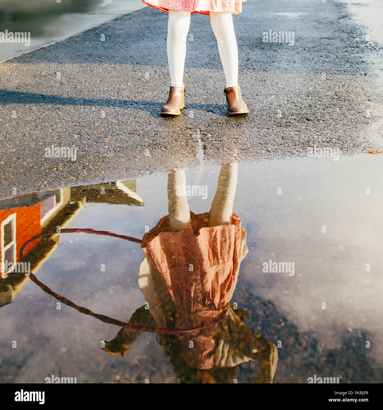 Mixed Race girl et plastique hoop reflète dans flaque Banque D'Images