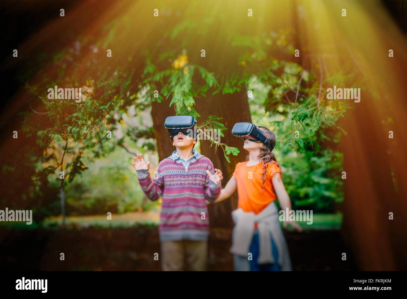 Mixed Race enfants utilisant des lunettes de réalité virtuelle à l'extérieur Banque D'Images