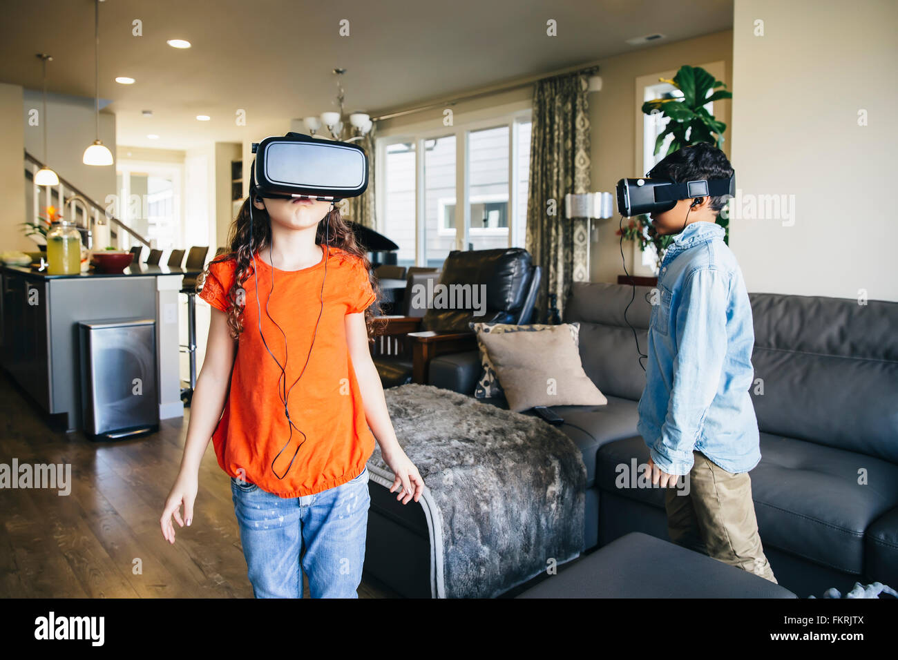 Mixed Race enfants utilisant des lunettes de réalité virtuelle dans la salle de séjour Banque D'Images