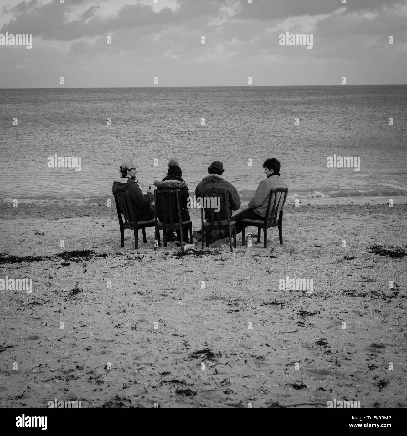 Quatre jeunes gens passent la soirée assis sur format chaise de salle à manger sur Gylllyngvase, Falmouth, Cornwall Banque D'Images