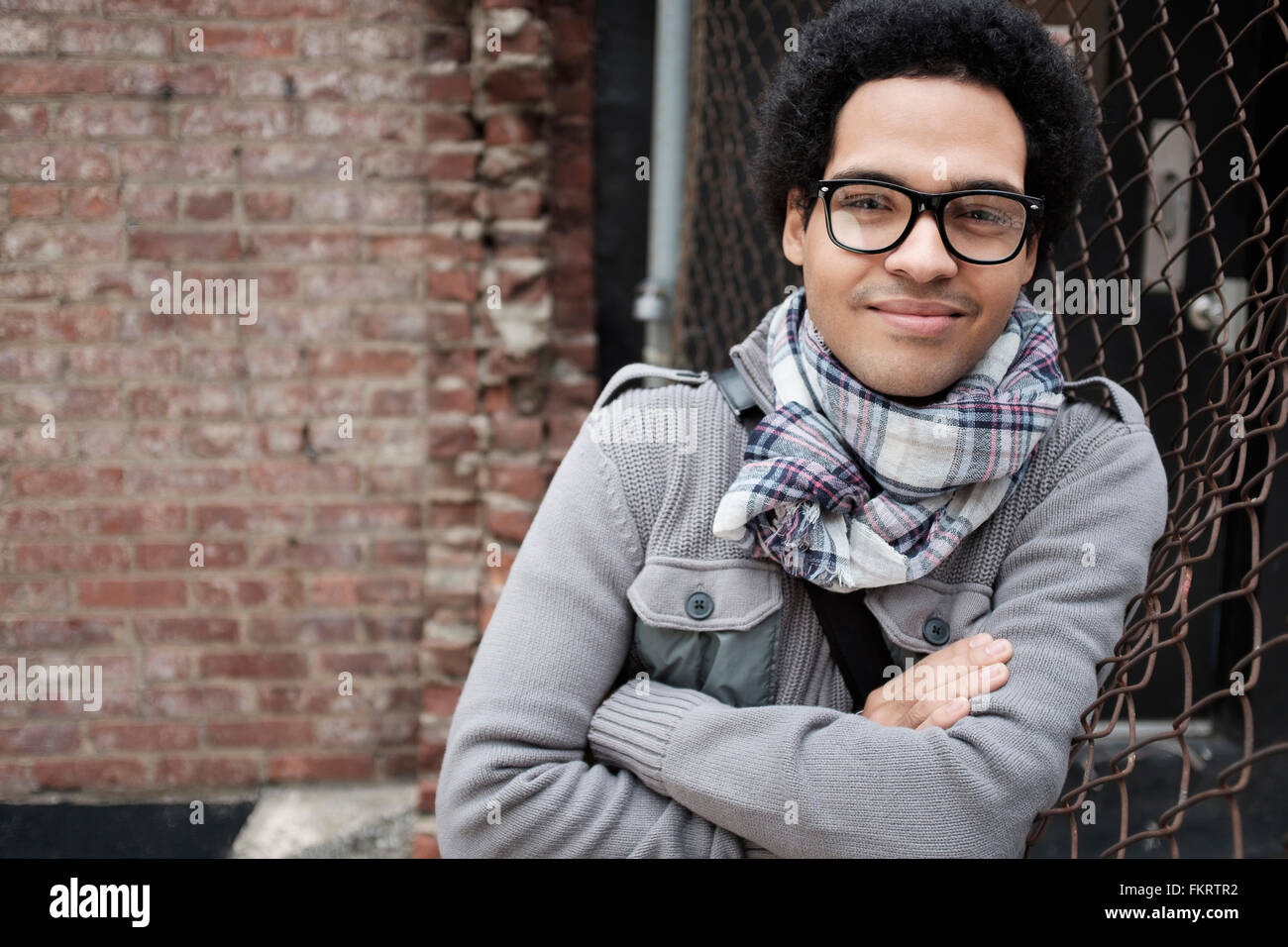 Mixed Race man leaning on chain link fence Banque D'Images