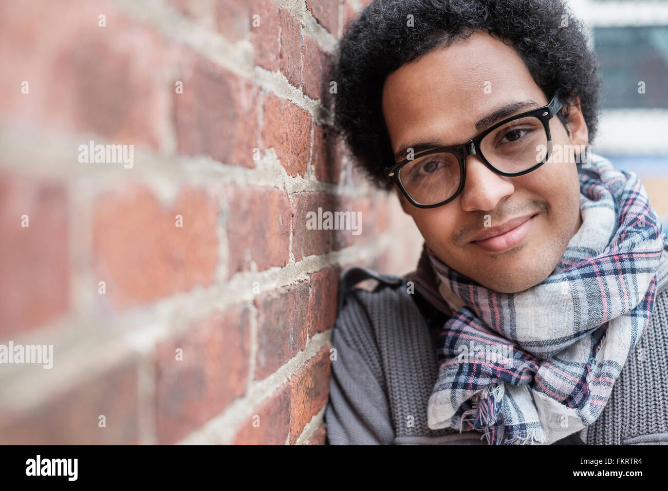 Mixed Race man leaning on brick wall Banque D'Images