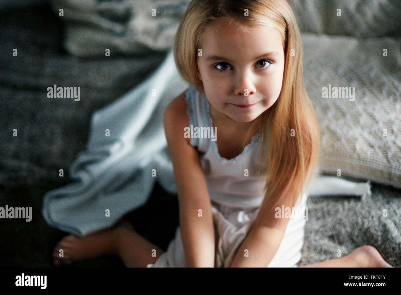 Caucasian girl smiling on bed Banque D'Images
