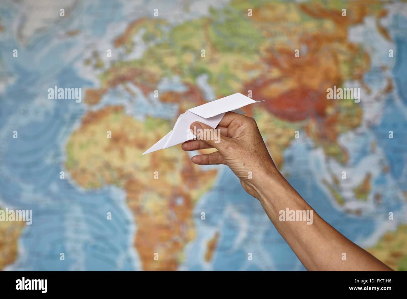 Hand holding paper plane, la carte du monde en arrière-plan Banque D'Images