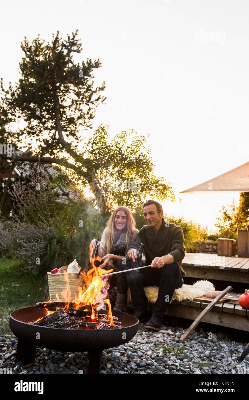 Couple sitting by fire pit in garden Banque D'Images