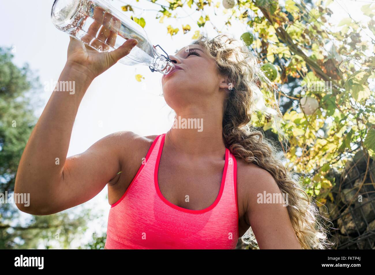 Jeune femme à boire l'eau de bouteille Banque D'Images