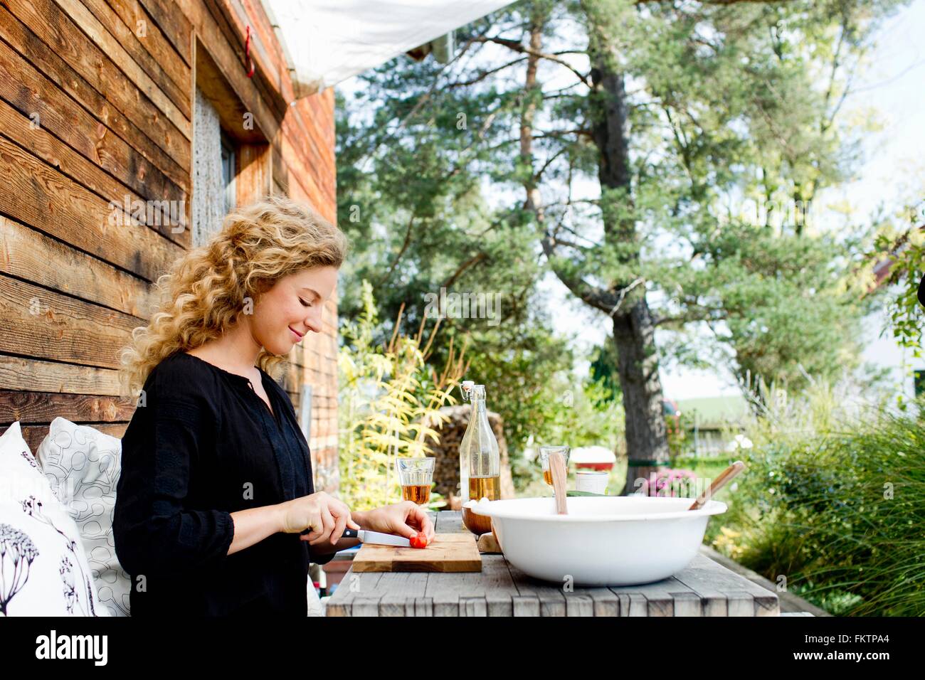 Jeune femme hacher les légumes à table outdoors Banque D'Images