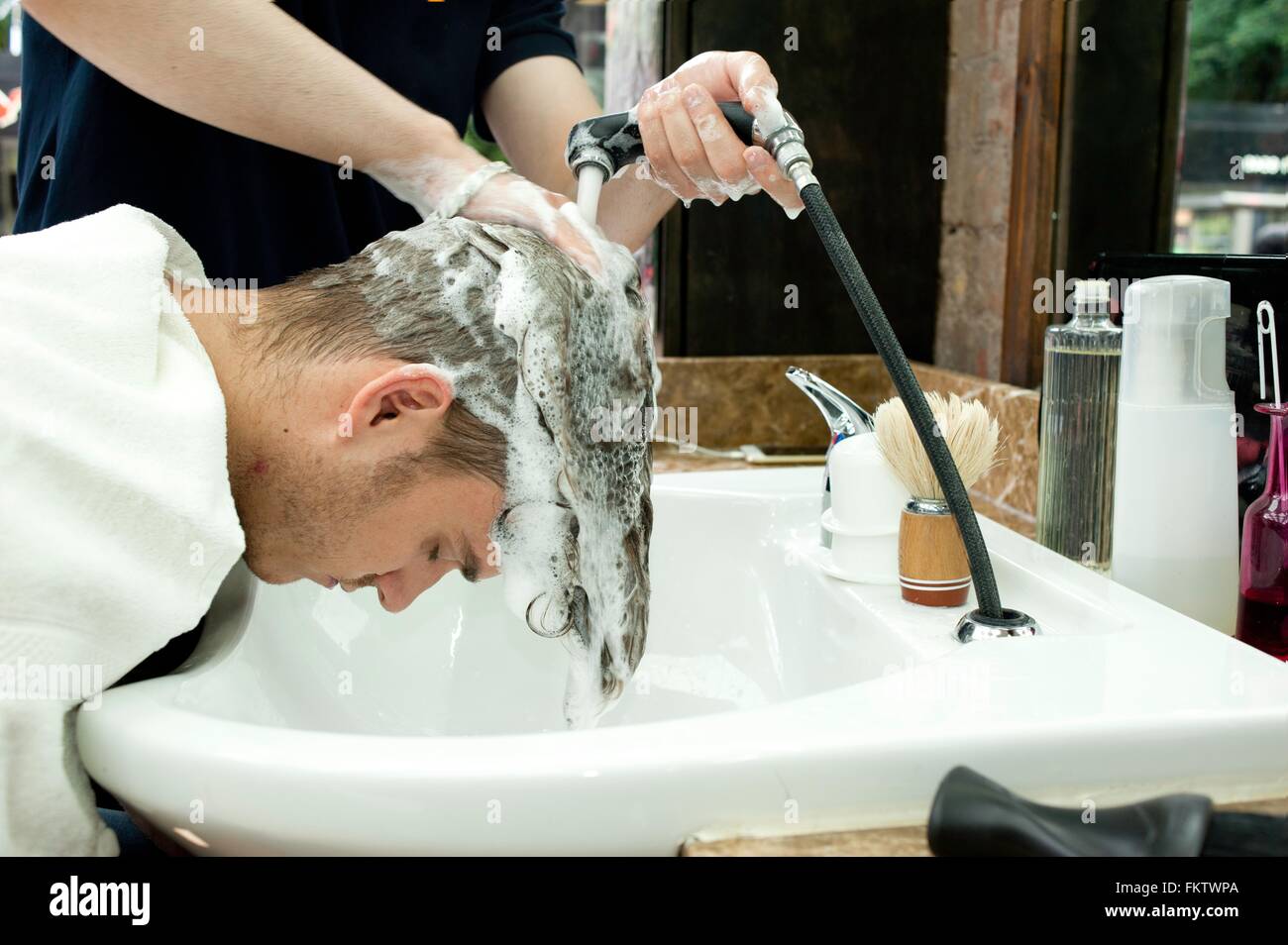 Vue latérale du jeune homme se pencher vers l'avant après avoir lavé les  cheveux dans un salon de barbier Photo Stock - Alamy