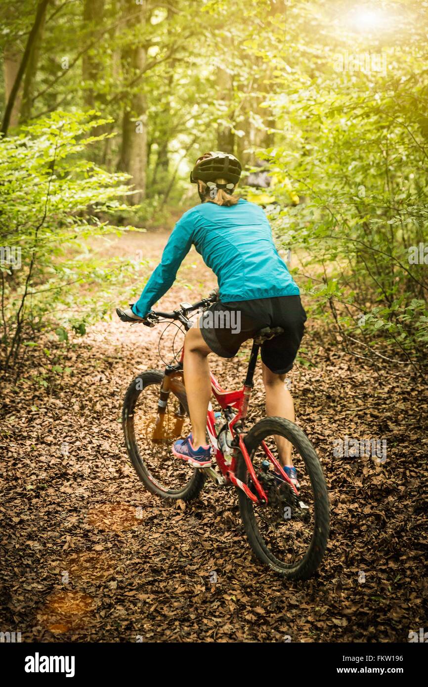 Vue arrière du vélo de montagne femelle mature sur piste forestière Banque D'Images