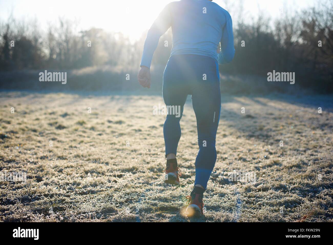 Vue arrière du coureur d'exécution sur l'herbe givrée Banque D'Images